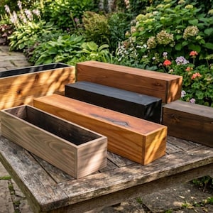 May include: A collection of rectangular wooden planters in various sizes and finishes, including natural, stained, and black. The planters are displayed on a weathered wooden table, with a lush garden background.