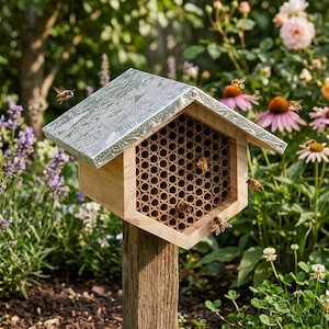 May include: A hexagonal wooden bee house featuring a metallic, embossed roof and a front panel filled with numerous small, hollow cylindrical tubes. Several bees are visible flying around and landing on the structure, which is mounted on a post.