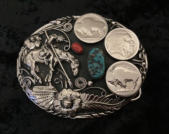 May include: Silver belt buckle with a Native American on horseback, surrounded by four buffalo nickels and turquoise and coral stones.