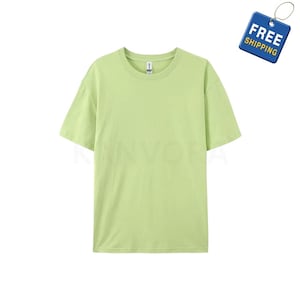 May include: A pale green, short-sleeved t-shirt with a crew neck. The shirt is a plain colour and looks to be made of a soft material. A blue tag with the words "FREE SHIPPING" is in the upper right corner.