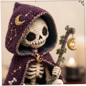 May include: A crocheted skeleton figure wearing a deep purple hooded cloak embroidered with gold stars, moons, and bone motifs. The figure holds a staff adorned with green leaves and a small, hanging gold crescent moon lantern charm.