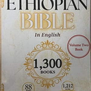 May include: The cover of "The Most Complete Ethiopian Bible" in English. The title is in large black letters with a gold-colored background. The cover also features the text "1,300 BOOKS" in a gold-colored design, and "Volume Two Book" in a red circle.
