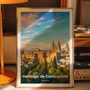 May include: A framed vertical art print featuring a painted landscape of Santiago de Compostela, Spain. The image displays a historic city skyline with a prominent cathedral, lush green trees in the foreground, and a blue sky with clouds.