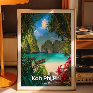 May include: A framed vertical art print featuring a tropical beach scene with turquoise water, limestone cliffs, and two wooden longtail boats. The foreground includes lush green palm leaves and red flowers. The text reads Koh Phi Phi THAILAND.