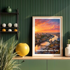 This contemporary Newcastle upon Tyne print celebrates the city's iconic riverscape — the Tyne Bridge and Millennium Bridge spanning the Tyne above the stacked quayside buildings, rendered with bold white NEWCASTLE typography and an open illustrated sky. Oak frame displayed against a deep green panelled wall alongside an oak console, black metal shelving, a yellow globe vase, white ceramic vessels, and layered botanicals.