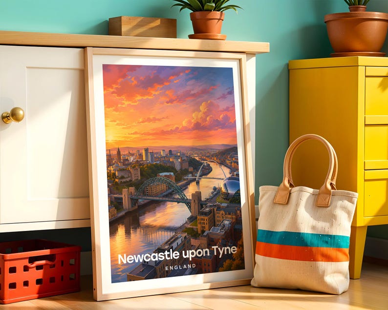 Newcastle upon Tyne poster capturing the Tyne Bridge spanning the river alongside the elegant arc of the Millennium Bridge and the warm-toned Victorian quayside facades, rendered in rich illustrative colour. Bold white NEWCASTLE typography and drifting clouds complete the composition. Oak frame leaning against a teal wall beside a white cabinet, yellow drawer unit, terracotta plant pots, a cloth bag, and a red plastic crate.