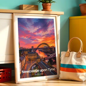 Newcastle upon Tyne poster capturing the Tyne Bridge over the River Tyne with the sweeping Georgian facades of Grey Street and the column of Grey's Monument rising behind, rendered in rich warm illustrative colour. Bold white NEWCASTLE UPON TYNE typography and drifting clouds complete the composition. Oak frame leaning against a teal wall beside a white cabinet, yellow drawer unit, terracotta plant pots, a cloth bag, and a red plastic crate.