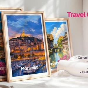 May include: Three framed art prints from a Premium Travel Collection featuring vibrant scenes of Marseille, France. The prints display a harbor with boats, a hilltop basilica at sunset, and a canal-side town, all encased in light wood frames.