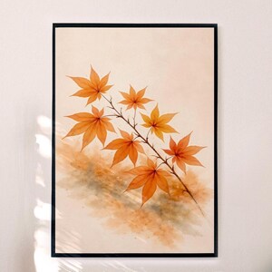 Puede incluir: Una impresión en acuarela enmarcada que presenta una rama de hojas de arce en tonos naranja y amarillo. Las hojas tienen vetas visibles, sobre un fondo suave de color melocotón. La obra de arte está encerrada en un marco negro.