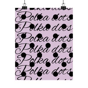 Peut inclure: Une affiche avec un motif répété de pois noirs et les mots "Polka dots" en cursive sur un fond violet clair. L'affiche est maintenue par deux pinces à reliure noires.