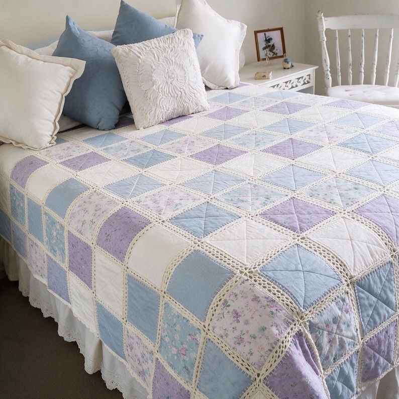 Pu&ograve; includere: Una trapunta patchwork caratterizzata da una griglia di pannelli quadrati in tessuto nelle tonalit&agrave; azzurro, lavanda e bianco, con alcuni quadrati che presentano un motivo floreale. I quadrati sono uniti da un bordo all'uncinetto color crema.