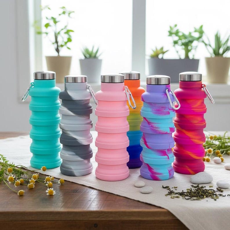 Puede incluir: Un conjunto de seis botellas de agua de silicona plegables con tapones de metal plateado y mosquetones adjuntos. Las botellas presentan varios colores, incluyendo turquesa s&oacute;lido, gris, rosa, naranja y dos patrones de remolinos multicolor.