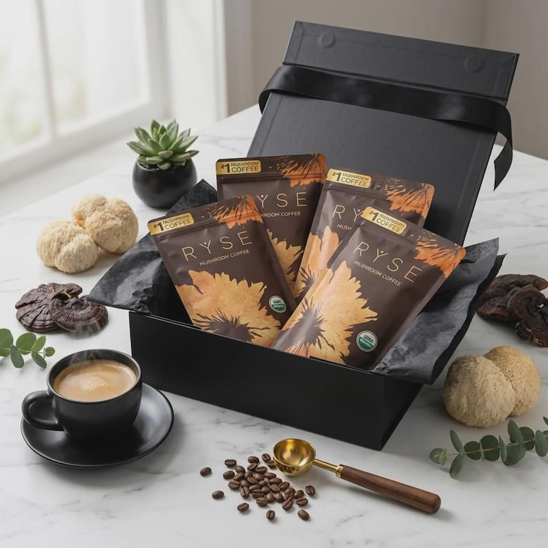 May include: A black gift box with four packets of RYSE mushroom coffee, a cup of coffee, coffee beans, and a gold scoop. The packets are brown with a sunflower design. Other items include a small succulent, and various mushrooms.