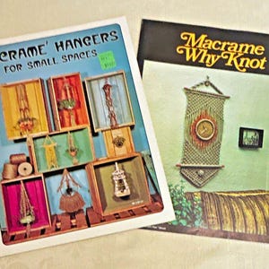 May include: Two instructional craft booklets. The left booklet is titled Macrame Hangers For Small Spaces and displays various macrame projects inside wooden crates. The right booklet is titled Macrame Why Knot and features a wall hanging.