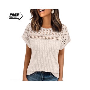 Pode incluir: Uma blusa bege de manga curta com textura de malha canelada na parte inferior e um painel de renda branca intrincado na parte superior do peito, ombros e mangas, finalizada com um decote redondo.