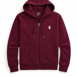 May include: A burgundy zip-up hoodie with a drawstring hood and front pockets. The hoodie features a white embroidered polo player logo on the left chest. The zipper is silver. The garment is made of a soft, comfortable material.