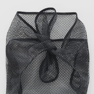 May include: Black mesh drawstring bag. The bag is made of a fine, open weave material. The drawstring is a thick, black cord that ties at the top. The bag is designed to be lightweight and flexible.