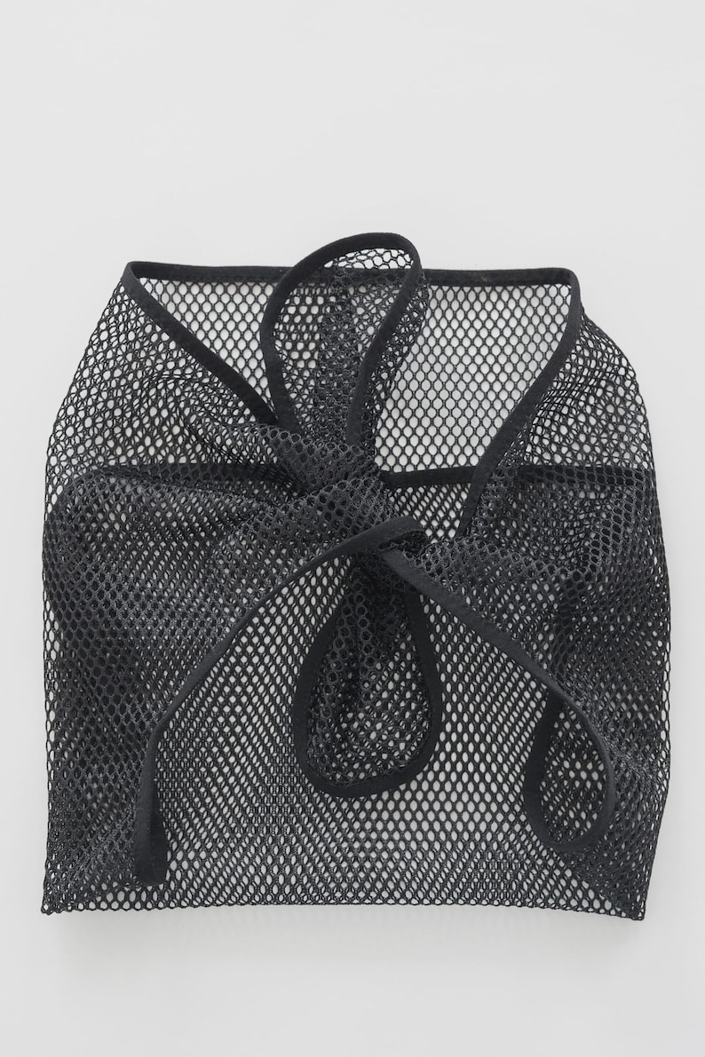Puede incluir: Bolsa negra de malla con cord&oacute;n. La bolsa est&aacute; hecha de un material de tejido abierto fino. El cord&oacute;n es un cord&oacute;n negro grueso que se ata en la parte superior. La bolsa es ligera y flexible.