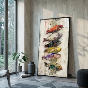 May include: A vertical rectangular framed wall art piece featuring a stack of six stylised fish painted in vibrant colours including red, silver, black, yellow, purple, and green, set against a textured off-white background with paint drips.