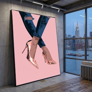 May include: A large rectangular wall art print featuring a stylized illustration of legs wearing dark blue distressed denim jeans and metallic rose gold high-heeled pumps against a solid light pink background, displayed in a black frame.