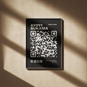 May include: A framed black and white poster featuring the text "AYOYI SUKAMA" and a QR code. The poster also includes the text "TOKYO 1991" and Japanese characters. The poster is displayed on a beige wall with shadows.