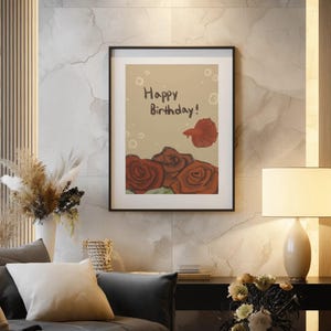 Puede incluir: Una impresión de arte mural enmarcada con fondo beige, el texto "Happy Birthday!" en marrón oscuro, un pez betta rojo nadando sobre tres rosas de color rojo oscuro y varias formas circulares claras de burbujas dispersas por el diseño.