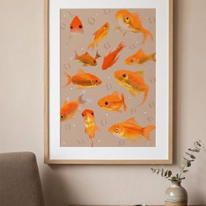 Op de afbeelding: Een ingelijste kunstdruk met illustraties van oranje goudvissen op een beige achtergrond. De goudvissen variëren in grootte en pose. Het kunstwerk zit in een houten lijst en wordt aan een muur getoond.