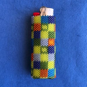 May include: A rectangular lighter encased in a hand-woven bead sleeve featuring a multi-colored checkered pattern. The beads are arranged in squares of lime green, navy blue, bright orange, light blue, and silver, with a red ignition button.
