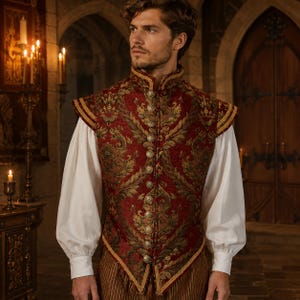 May include: A sleeveless vest featuring a deep red and gold damask pattern with a high collar and a vertical row of metallic buttons. The vest is worn over a white long-sleeved shirt with full sleeves and gathered cuffs, paired with brown trousers.