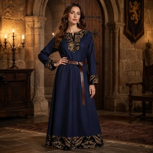 Puede incluir: Un vestido largo de color azul marino con mangas largas, puños con estampado negro y dorado, escote a juego y un dobladillo ancho. La prenda se ajusta a la cintura con un cinturón fino de cuero marrón que cuelga por la parte delantera.