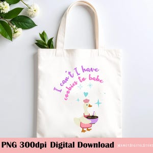 May include: A white canvas tote bag featuring a graphic of a goose wearing a pink chef hat and apron, holding a purple mixing bowl and whisk. The text reads, I can't I have cookies to bake, accompanied by small blue star and heart illustrations.
