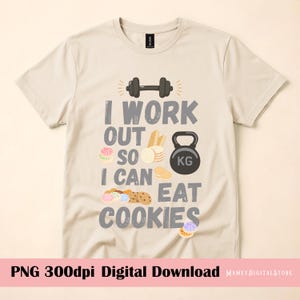 May include: A beige short-sleeve t-shirt featuring a dark gray dumbbell icon and the text I WORK OUT SO I CAN EAT COOKIES in dark gray lettering. The design includes various illustrations of cookies and a black kettlebell labeled with KG.