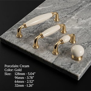 May include: Three gold-toned metal cabinet pulls with cream-colored porcelain centers in varying lengths of 128mm (5.04 inches), 96mm (3.78 inches), and 64mm (2.52 inches), plus one round cream porcelain knob measuring 32mm (1.26 inches).