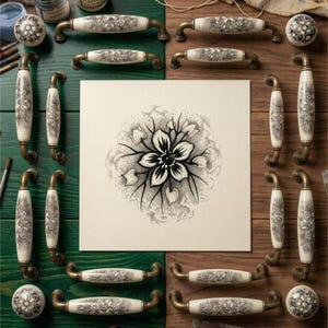May include: A collection of ceramic cabinet hardware featuring cream-colored surfaces with intricate black floral patterns and antique brass-toned metal accents. The set includes various drawer pulls and round knobs arranged around a central floral print.