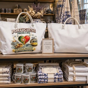 Peut inclure: Deux sacs fourre-tout en toile blanche avec des anses en corde. Le sac de gauche présente un motif avec un drapeau portugais en forme de cœur, un tramway jaune, une tasse de café et le texte : PORTUGUESE PROBLEMS, TOO MUCH SAUDADE, NOT ENOUGH PORTUGAL.