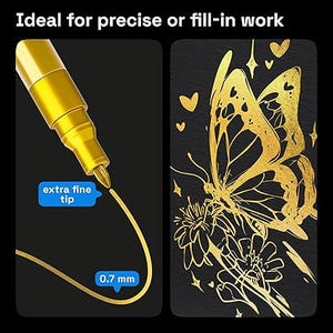 May include: A gold extra fine tip marker with a 0.7 mm tip is shown on a black background. The marker is creating a gold line. Next to it is a gold butterfly and flower design on a black background.