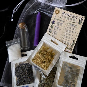 May include: A manifestation kit containing a purple candle, a clear glass vial with a cork stopper, a small bag of white salt, and four labeled pouches containing dried jasmine, lavender, mugwort, and moonstone, plus an instructional card.