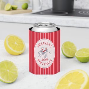 May include: A red and white vertical striped can cooler featuring a central oval emblem with the text Melissa's 30th Birthday and a graphic illustration of multiple hands holding up wine glasses for a toast in a celebratory design.