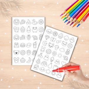 May include: Two white rectangular sheets featuring black line art illustrations of various small icons including animals, food items, celestial shapes, and plants. A red marker is positioned on one sheet, and a set of colored pencils is nearby.