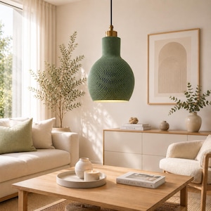 Peut inclure: Une suspension vert olive mat avec une surface texturée et alvéolée, surmontée d'une fixation en métal doré. La lampe est suspendue par un cordon noir et présente un corps large et arrondi qui se rétrécit vers le haut, diffusant une lumière chaude.