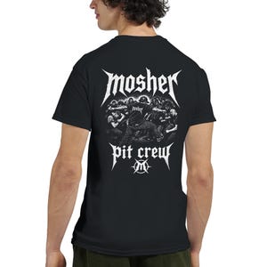 Peut inclure: Un t-shirt noir à manches courtes avec un motif blanc au dos. Le dessin représente une foule dans un mosh pit avec le texte "mosher" au-dessus et "pit crew" en dessous, centré autour d'un logo "M" stylisé dans un emblème circulaire.