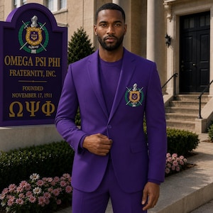 May include: A vibrant purple suit jacket featuring a matching purple t-shirt underneath. The jacket displays an embroidered crest on the left chest with crossed swords and a helmet. The text OMEGA PSI PHI FRATERNITY, INC. FOUNDED NOVEMBER 17, 1911 is visible.