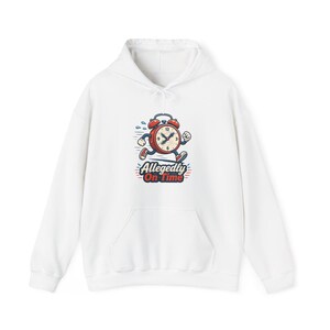 Peut inclure: Un sweat-shirt à capuche blanc avec un motif représentant un réveil rouge de dessin animé courant avec des bras et des jambes. Le texte sous le réveil indique Allegedly On Time dans une police bleue et rouge. Il possède une poche kangourou.
