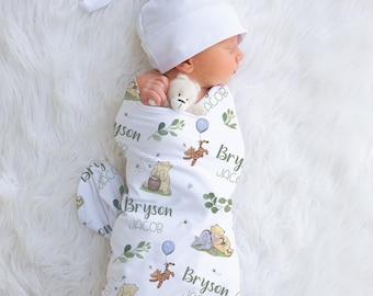 May include: A newborn baby wrapped in a white swaddle blanket and matching cap. The blanket features a Winnie the Pooh design with the name "Bryson Jacob" printed on it. A small stuffed bear is held by the baby.