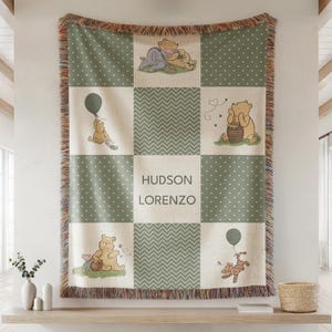 May include: A woven blanket featuring a patchwork design with Winnie the Pooh characters. The blanket has a green and white polka dot pattern, with a central panel displaying the names "HUDSON LORENZO". The blanket has a fringed edge.