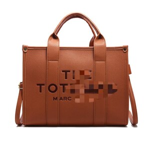 May include: A brown tote bag with top handles and a shoulder strap. The bag features the text "TOT" and "MARC" in a darker brown color. The bag has a rectangular shape and is made of a smooth material.