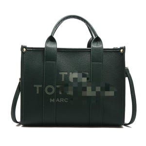 May include: A dark green tote bag with the text "THE TOTE BAG MARC" in silver lettering. The bag has two top handles and a detachable shoulder strap. The bag is rectangular in shape.