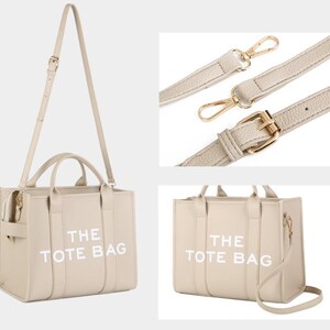 Pu&ograve; includere: Borsa tote beige con la scritta "THE TOTE BAG" in bianco. La borsa ha una tracolla e due manici. La borsa ha finiture color oro. La borsa &egrave; realizzata in un materiale liscio.