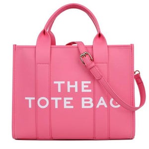 Pu&ograve; includere: Una borsa tote rosa acceso con la scritta bianca "THE TOTE BAG". La borsa ha due manici superiori e una tracolla staccabile con fibbia dorata. La borsa &egrave; realizzata in materiale liscio.
