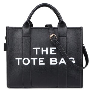 Pu&ograve; includere: Borsa tote nera con la scritta "THE TOTE BAG" in lettere bianche. La borsa ha due manici superiori e una tracolla staccabile con fibbia color oro. La borsa &egrave; realizzata in materiale strutturato.